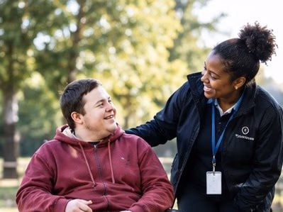 A support worker chatting with a young man in a wheelchair outdoors